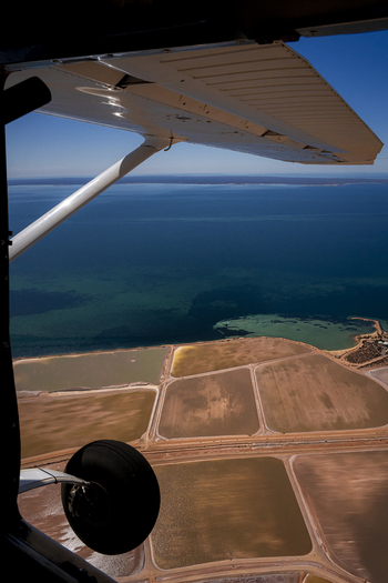 Aerial view of the industrial salt pans at Useless Loop showing brown and yellow water patterns adjacent to the turquoise ocean in Kalbarri Western Australia Australia. Aerial view of the industrial salt pans at Useless Loop showing brown and yellow water patterns adjacent to the turquoise ocean in Kalbarri Western Australia Australia.