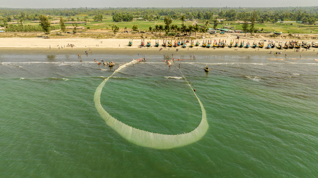 Aerial view of fishing nets cast a shimmering circle in the turquoise sea against the backdrop of sandy shores Cox s Bazar Chittagong Division Bangladesh. Aerial view of fishing nets cast a shimmering circle in the turquoise sea against the backdrop of sandy shores Cox s Bazar Chittagong Division Bangladesh.