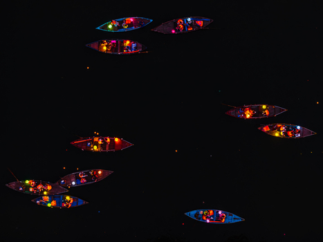 Aerial view of small wooden boats illuminated with colorful lanterns floating on dark water at night in Vietnam. Aerial view of small wooden boats illuminated with colorful lanterns floating on dark water at night in Vietnam.