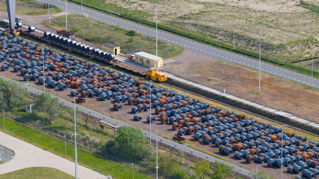 Aerial view of the Tata Steel industrial site featuring rows of large steel coils stored outdoors next to a yellow transport vehicle and a railway track in Velsen Noord Noord Holland Netherlands. Aerial view of the Tata Steel industrial site featuring rows of large steel coils stored outdoors next to a yellow transport vehicle and a railway track in Velsen Noord Noord Holland Netherlands.
