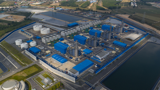 Aerial view of the Gulf Pluak Daeng Power Plant with its blue industrial buildings white storage tanks and cooling towers in Map Yang Phon Rayong Thailand.