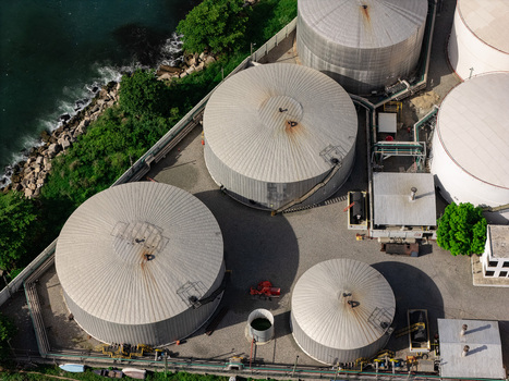 Aerial view of large industrial storage tanks situated along the coastline featuring metallic cylindrical structures and surrounding infrastructure in Bajos de Haina San Cristobal Provinc Dominican Republic.