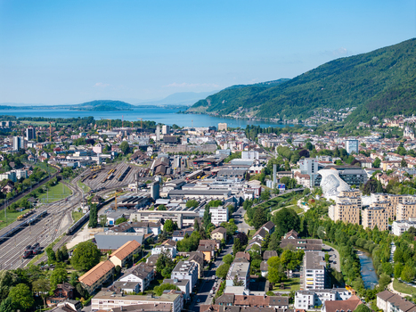 Aerial view of the industrial area and railway tracks near the city center with Lake Biel and lush green hills in the background Biel Bienne Canton of Bern Switzerland.