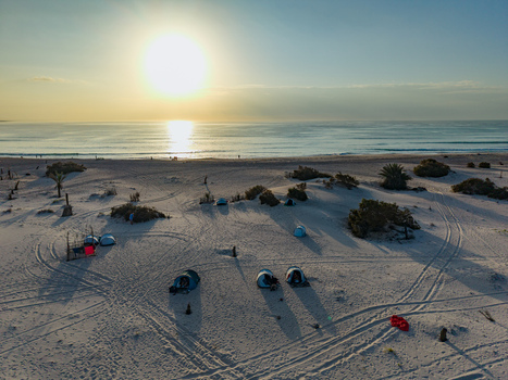 Aerial view of tents scattered across the sandy beach where the turquoise sea meets the golden horizon Kadrihnitin Socotra Yemen. Aerial view of tents scattered across the sandy beach where the turquoise sea meets the golden horizon Kadrihnitin Socotra Yemen.