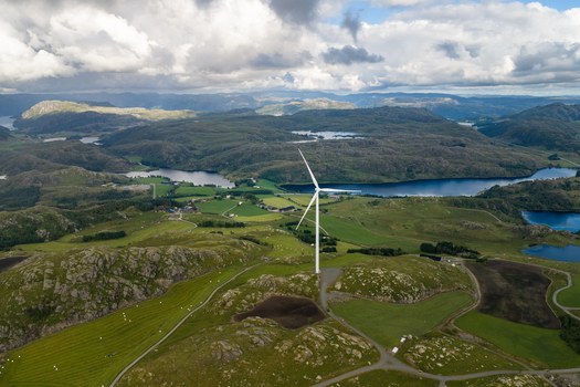Aerial view of Makaknuten Vindkraftverk wind turbine standing on a grassy hill overlooking lakes and rolling mountains in Bjerkreim Municipality Rogaland Norway. Aerial view of Makaknuten Vindkraftverk wind turbine standing on a grassy hill overlooking lakes and rolling mountains in Bjerkreim Municipality Rogaland Norway.
