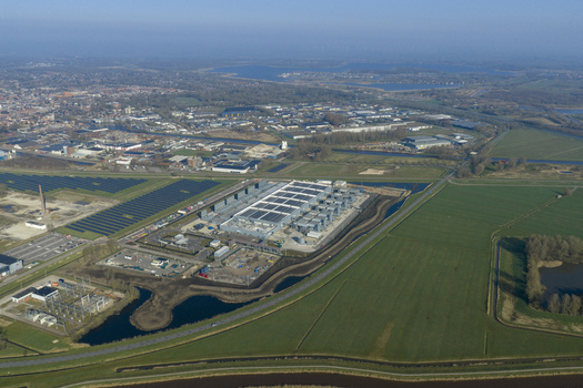 Aerial view of a digital data center facility with solar panels on the roof surrounded by green fields and a solar farm Netherlands. Aerial view of a digital data center facility with solar panels on the roof surrounded by green fields and a solar farm Netherlands.