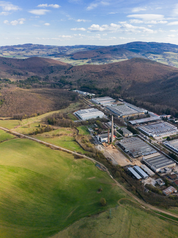 Aerial view of the PPS GROUP a.s. factory complex amidst rolling hills and verdant fields under a vast sky Detva Banskobystricky kraj Slovakia. Aerial view of the PPS GROUP a.s. factory complex amidst rolling hills and verdant fields under a vast sky Detva Banskobystricky kraj Slovakia.