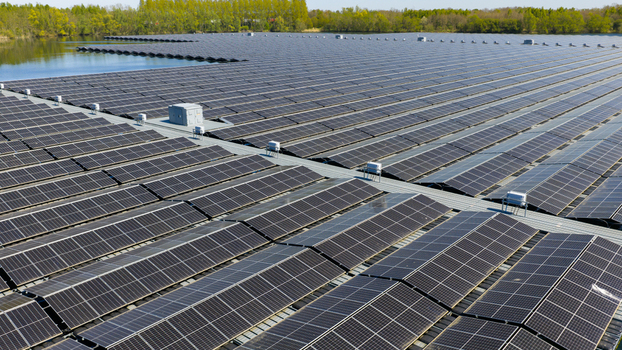 Aerial view of a vast floating solar farm with rows of photovoltaic panels on a calm lake surrounded by lush green trees under a clear sky Zwolle Overijssel Netherlands. Aerial view of a vast floating solar farm with rows of photovoltaic panels on a calm lake surrounded by lush green trees under a clear sky Zwolle Overijssel Netherlands.