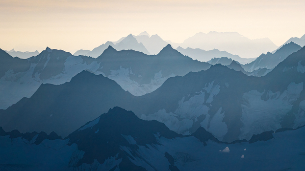 Aerial view of the snow capped peaks of Chugach State Park with layered mountain ranges fading into the hazy distance in Anchorage Alaska United States. Aerial view of the snow capped peaks of Chugach State Park with layered mountain ranges fading into the hazy distance in Anchorage Alaska United States.