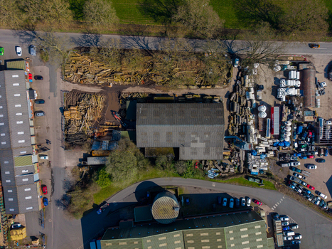 Aerial view of Ladfordfields Industrial Estate featuring industrial buildings piles of timber storage areas and a parking lot with cars in Stafford England United Kingdom. Aerial view of Ladfordfields Industrial Estate featuring industrial buildings piles of timber storage areas and a parking lot with cars in Stafford England United Kingdom.