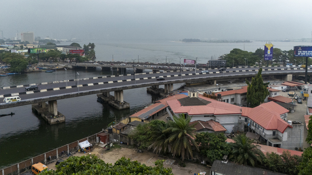 Aerial view of Lagos Island featuring bridge infrastructure urban buildings and surrounding water under a cloudy sky Lagos Lagos Nigeria. Aerial view of Lagos Island featuring bridge infrastructure urban buildings and surrounding water under a cloudy sky Lagos Lagos Nigeria.