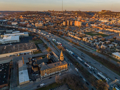 Aerial view of the highway cutting through the city with buildings and a clock tower casting long shadows in the warm light Cincinnati Ohio United States. Aerial view of the highway cutting through the city with buildings and a clock tower casting long shadows in the warm light Cincinnati Ohio United States.