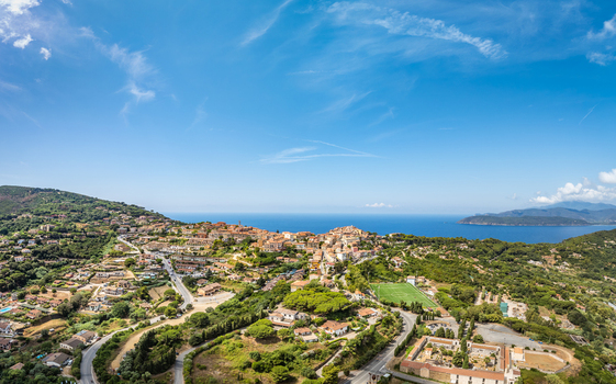 Aerial view of the historic town of Capoliveri nestled on the hills of the island of Elba with surrounding Mediterranean landscape and blue sea in Capoliveri Tuscany Italy.