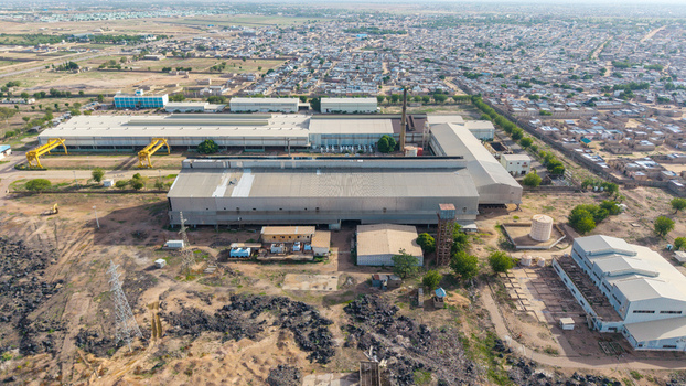 Aerial view of Katsina Steel Rolling Co. Ltd with industrial buildings metal rooftops and surrounding landscape in Katsina Katsina Nigeria.