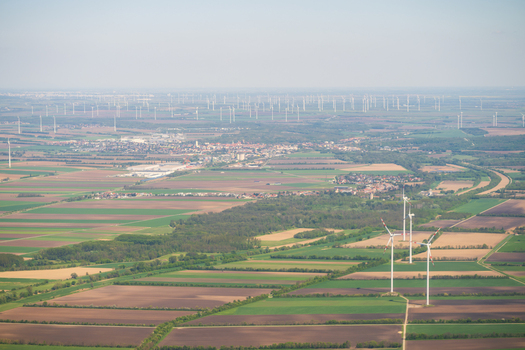 Aerial view of wind turbines standing in vast agricultural fields under a clear sky near a small town Lower Austria Austria. Aerial view of wind turbines standing in vast agricultural fields under a clear sky near a small town Lower Austria Austria.