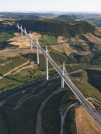 Aerial view of Millau Viaduct piercing the landscape its sleek lines contrasting with the rolling hills and verdant valleys Millau France. Aerial view of Millau Viaduct piercing the landscape its sleek lines contrasting with the rolling hills and verdant valleys Millau France.