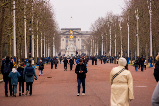 London United Kingdom 12 May 2025 View of Buckingham Palace and the Victoria Memorial at the end of The Mall with crowds of people walking under a cloudy sky.
