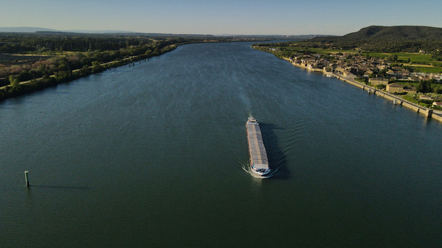 Aerial view of a cargo barge navigating the Rhone river past the village of Saint Etienne des Sorts Occitanie France. Aerial view of a cargo barge navigating the Rhone river past the village of Saint Etienne des Sorts Occitanie France.