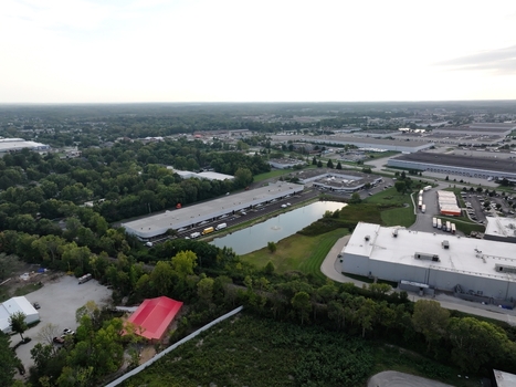 Aerial view of industrial warehouses a small pond and surrounding green trees in an urban area in Indianapolis Indiana United States. Aerial view of industrial warehouses a small pond and surrounding green trees in an urban area in Indianapolis Indiana United States.
