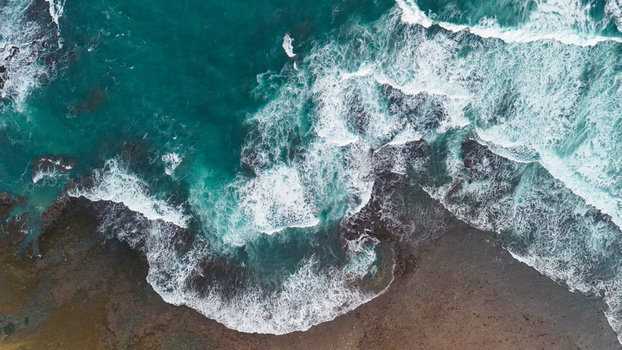 Aerial view of waves crashing against the rocky shoreline of a beach in Indonesia. Aerial view of waves crashing against the rocky shoreline of a beach in Indonesia.
