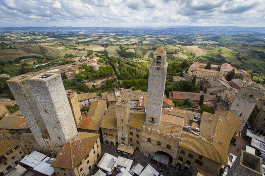 View of medieval towers piercing the skyline above terracotta roofs amidst rolling hills under a vast sky in San Gimignano Tuscany Italy. View of medieval towers piercing the skyline above terracotta roofs amidst rolling hills under a vast sky in San Gimignano Tuscany Italy.