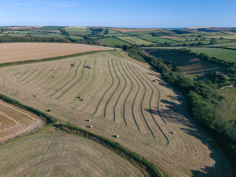 Aerial view of agricultural farmland with freshly harvested fields hay bales hedgerows and rural tracks in Looe Cornwall United Kingdom. Aerial view of agricultural farmland with freshly harvested fields hay bales hedgerows and rural tracks in Looe Cornwall United Kingdom.