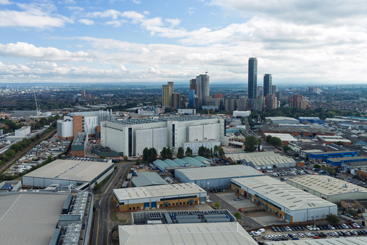 Aerial view of a large data center facility surrounded by industrial warehouses and a distant urban skyline under a cloudy sky in the United Kingdom. Aerial view of a large data center facility surrounded by industrial warehouses and a distant urban skyline under a cloudy sky in the United Kingdom.