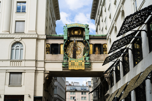 View of the historic Anker Clock with its intricate Art Nouveau design and golden figures bridging two white buildings under a bright sky Vienna Vienna Austria. View of the historic Anker Clock with its intricate Art Nouveau design and golden figures bridging two white buildings under a bright sky Vienna Vienna Austria.