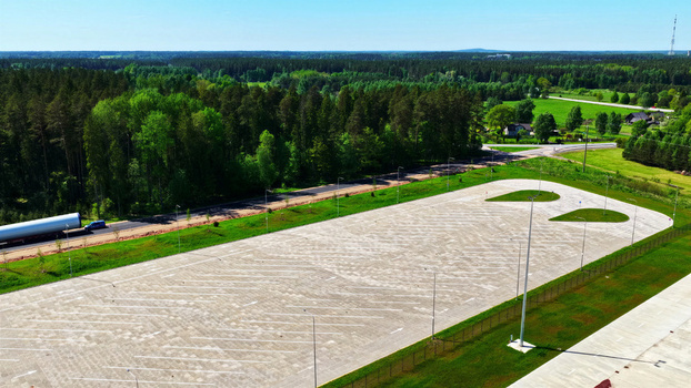 Aerial view of an empty paved parking lot surrounded by lush green grass and a dense forest in Latvia. Aerial view of an empty paved parking lot surrounded by lush green grass and a dense forest in Latvia.