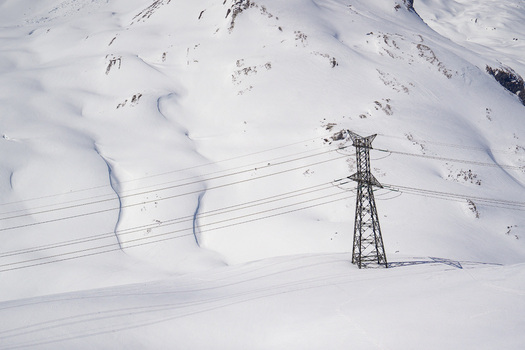 Aerial view of a high voltage electricity pylon and power lines crossing the snow covered slopes of Colle del Piccolo San Bernardo in La Thuile Valle d Aosta Italy. Aerial view of a high voltage electricity pylon and power lines crossing the snow covered slopes of Colle del Piccolo San Bernardo in La Thuile Valle d Aosta Italy.