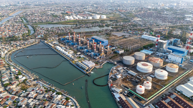 Aerial view of a large power plant facility with industrial storage tanks chimneys and surrounding urban infrastructure in Semarang Central Java Indonesia. Aerial view of a large power plant facility with industrial storage tanks chimneys and surrounding urban infrastructure in Semarang Central Java Indonesia.
