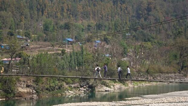View of a suspension bridge with people walking Nepal.