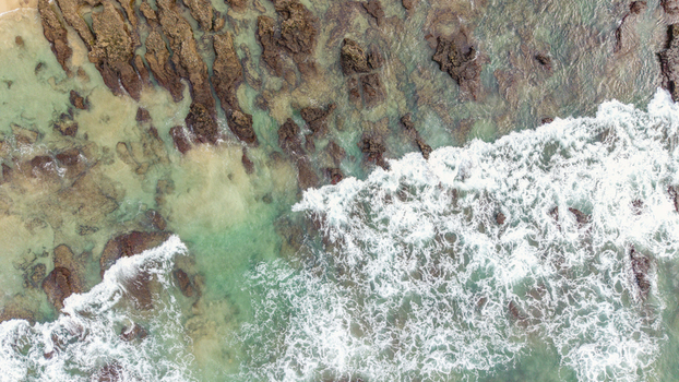 Aerial view of waves crashing against the rocky shoreline of Hartenbos with turquoise water and white foam Mossel Bay Western Cape South Africa. Aerial view of waves crashing against the rocky shoreline of Hartenbos with turquoise water and white foam Mossel Bay Western Cape South Africa.