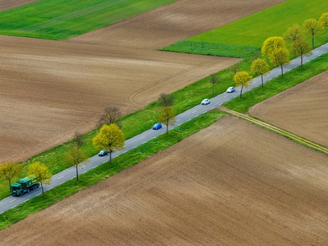 Aerial view of a road slicing through the earth lined with trees cars and fields of green and brown Neuf Brisach Grand Est France.