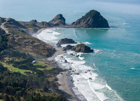 Aerial view of the rugged Southern Oregon Coast featuring dramatic sea stacks waves and a winding coastal highway near Port Orford Oregon United States. Aerial view of the rugged Southern Oregon Coast featuring dramatic sea stacks waves and a winding coastal highway near Port Orford Oregon United States.