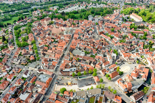 Aerial view of Hauptstrasse surrounded by historic red tiled rooftops the parish church and lush green trees in Forchheim Bayern Germany.