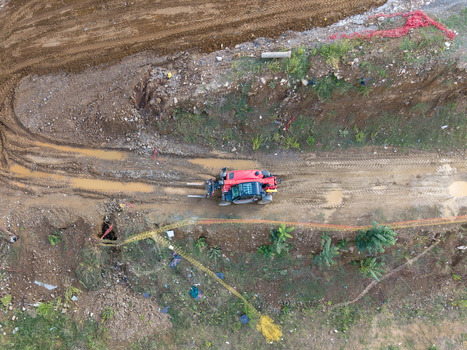 Aerial view of a red utility vehicle driving on a muddy dirt path surrounded by excavated earth and sparse vegetation in Istanbul Istanbul Turkiye. Aerial view of a red utility vehicle driving on a muddy dirt path surrounded by excavated earth and sparse vegetation in Istanbul Istanbul Turkiye.