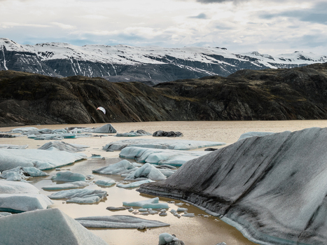 Aerial view of Vatnajokull glacier with floating icebergs in a glacial lagoon rugged mountains in the background and cloudy sky Iceland.
