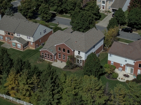 Aerial view of a suburban neighborhood featuring brick houses with shingled roofs green lawns and mature trees in Mason Ohio United States.