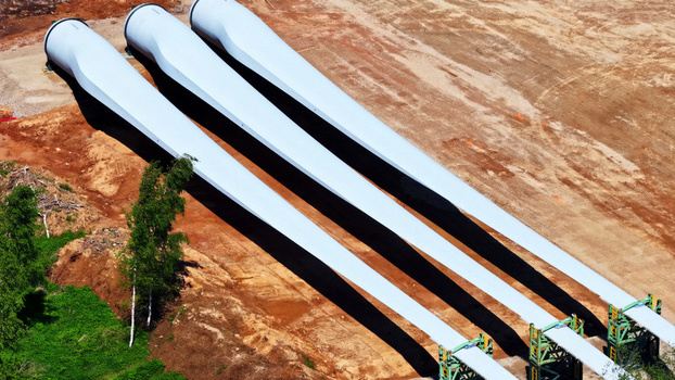 Aerial view of three large wind turbine blades resting on the ground at a construction site in Latvija. Aerial view of three large wind turbine blades resting on the ground at a construction site in Latvija.