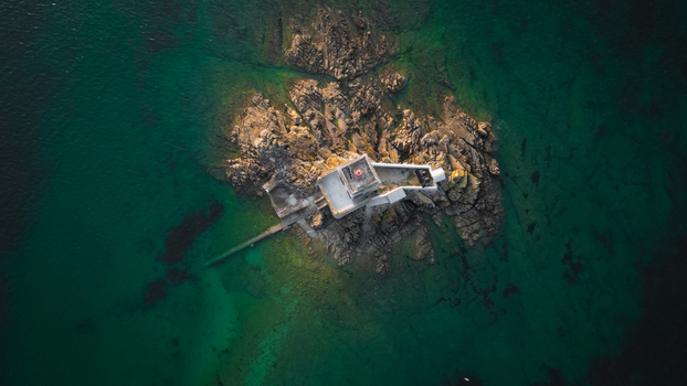 Aerial view of a ile noire perched on a rocky islet surrounded by the emerald sea contrasting the rugged stone with the tranquil water Plouezoc h Finistere France.