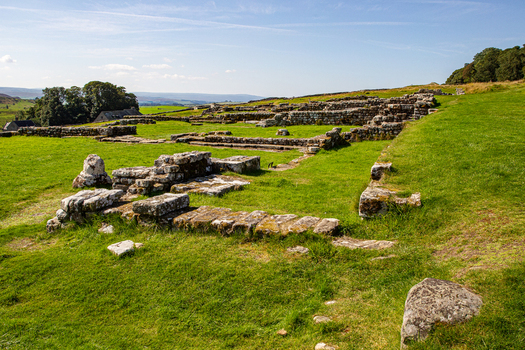 View of the ancient Roman stone foundations at Vindolanda archaeological site surrounded by green fields and rolling hills in Hexham England United Kingdom. View of the ancient Roman stone foundations at Vindolanda archaeological site surrounded by green fields and rolling hills in Hexham England United Kingdom.
