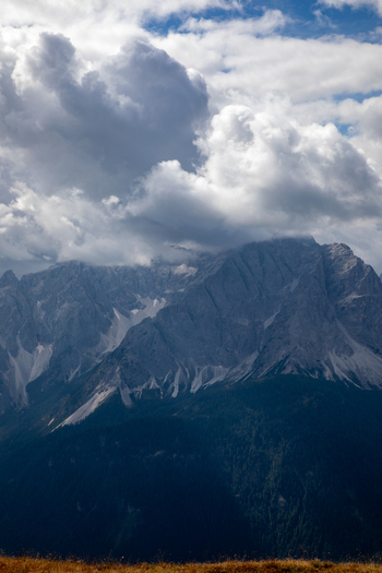 Aerial view of the Dolomites mountain range with dramatic clouds over the rocky peaks and forested slopes in Rocca Pietore Veneto Italy.