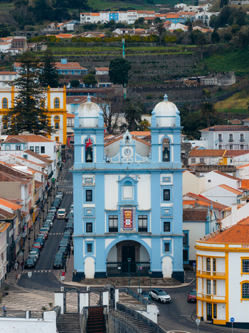 Aerial view of the blue Igreja da Misericordia church surrounded by historic white buildings and terraced hills in Angra do Heroismo Azores Portugal.