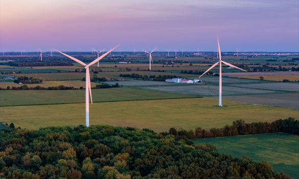 Aerial view of wind turbines standing in agricultural fields near a forest during golden hour in Lakeshore Ontario Canada. Aerial view of wind turbines standing in agricultural fields near a forest during golden hour in Lakeshore Ontario Canada.