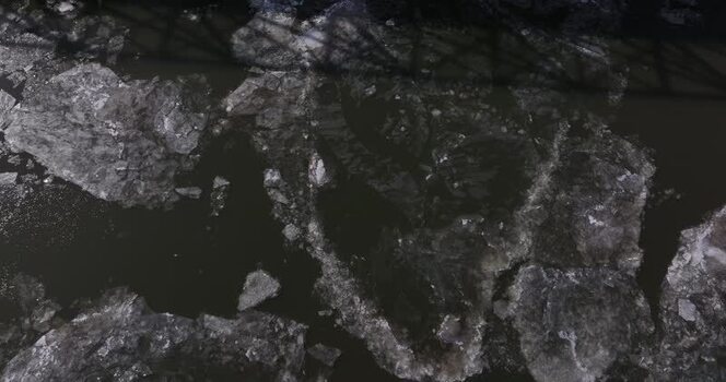 Aerial view of large ice floes floating on a dark river United States.