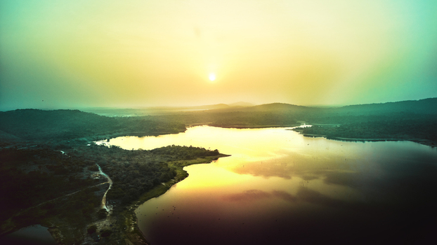Aerial view of Owala Dam at sunset with calm water reflecting the golden light surrounded by lush green hills and dense vegetation in Osogbo Osun Nigeria. Aerial view of Owala Dam at sunset with calm water reflecting the golden light surrounded by lush green hills and dense vegetation in Osogbo Osun Nigeria.