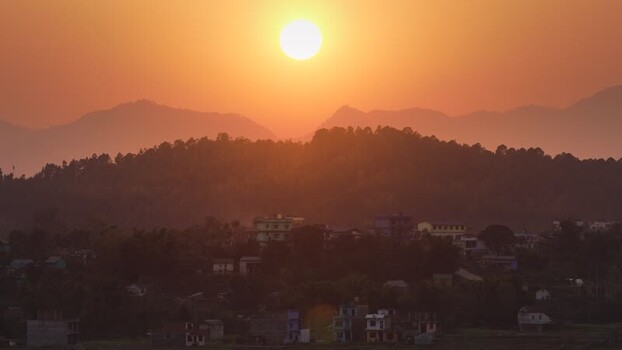 View of a sunset over a village and hills Nepal.