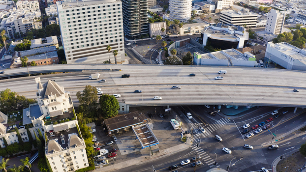 Aerial view of a busy highway interchange with surrounding urban buildings a historic hotel and city streets in Los Angeles California United States.