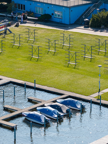 Aerial view of the Berlin Grunau Regatta Course with boats covered in blue tarps metal racks on a green lawn and a blue building in Berlin Berlin Germany. Aerial view of the Berlin Grunau Regatta Course with boats covered in blue tarps metal racks on a green lawn and a blue building in Berlin Berlin Germany.